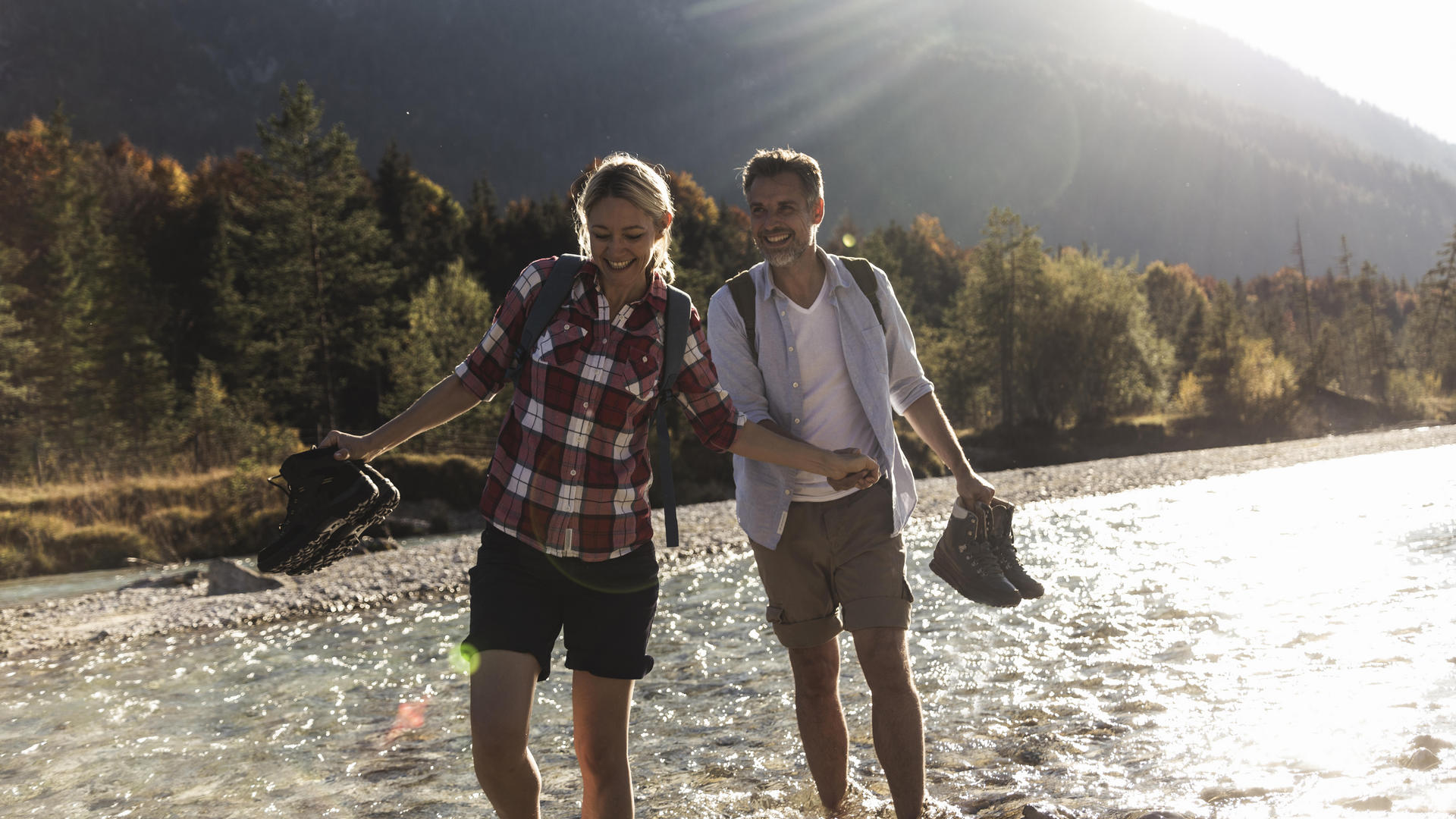 Couple Hiking through stream with shoes off in Spring