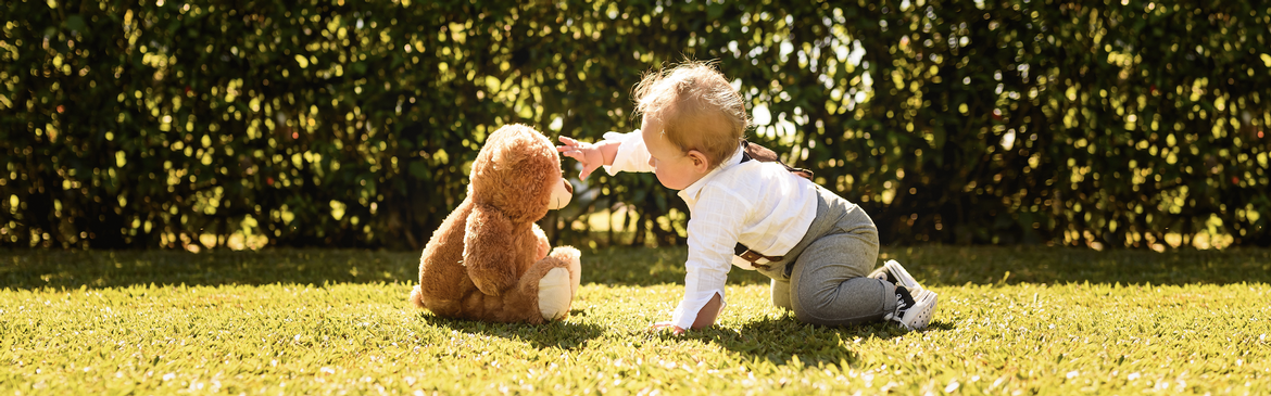 kid crawling and reaching for teddy bear