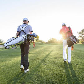 two men walking on fairway with golf bags