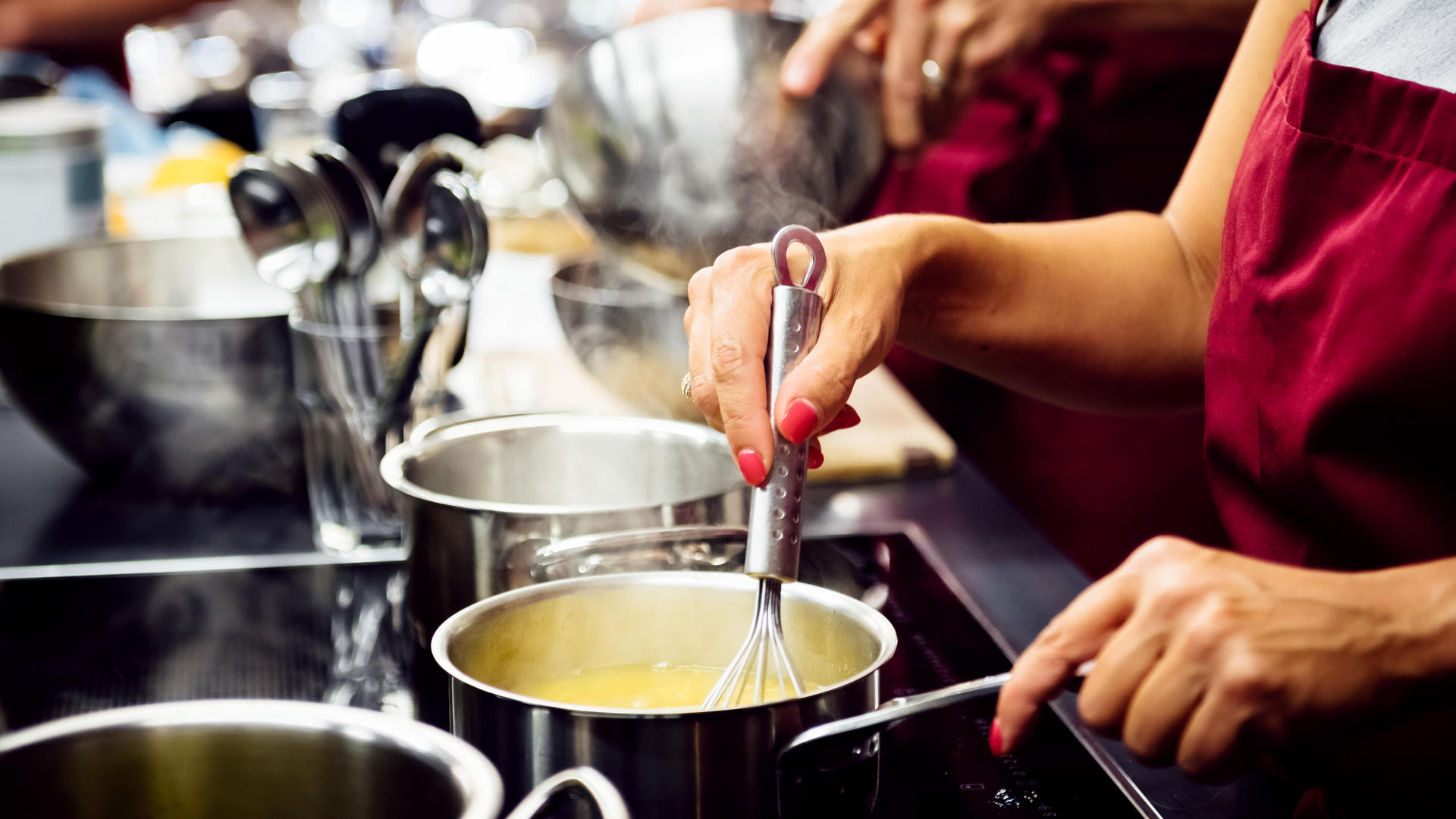 woman whisking a white sauce in a stainless steal pot