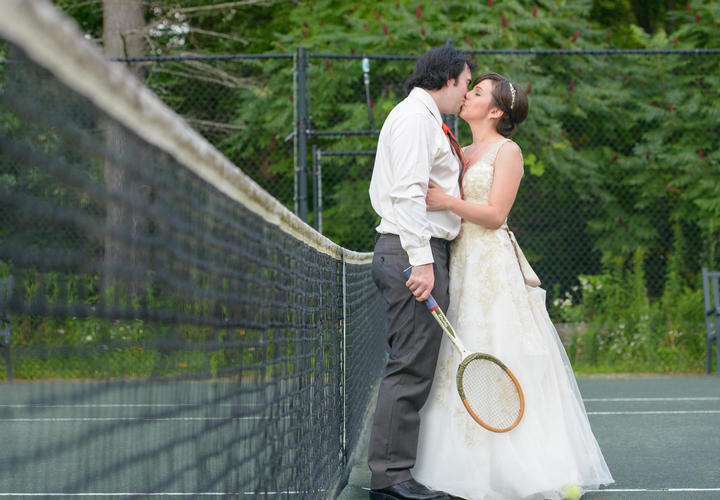 newlywed couple kissing on a tennis court