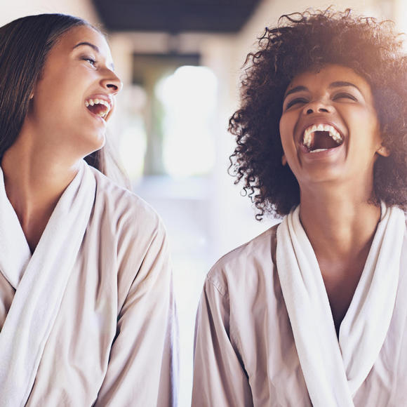 two women in white spa robes laughing